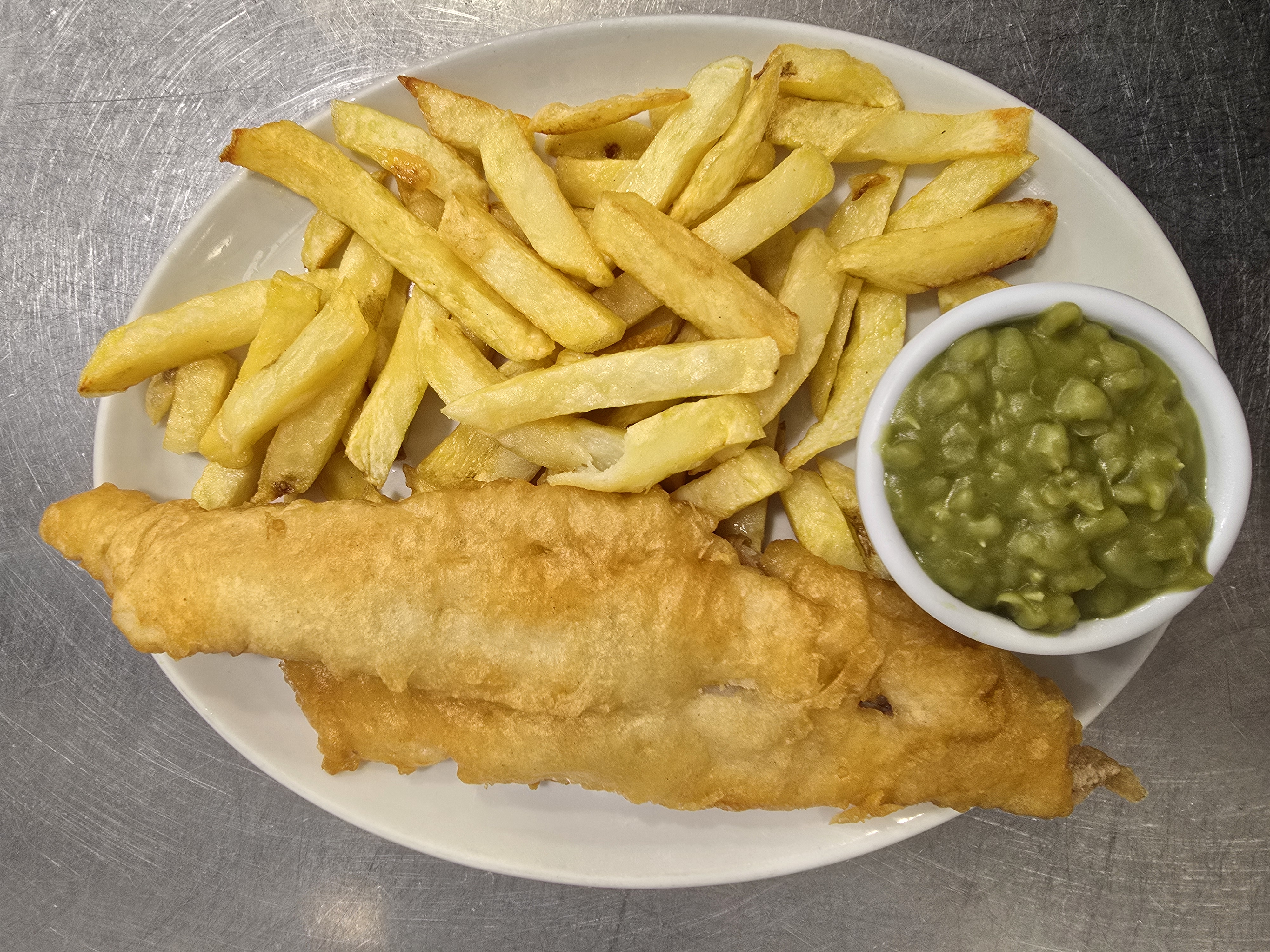 A plate of sumptuous Fish & Chips with a side of Mushy Peas